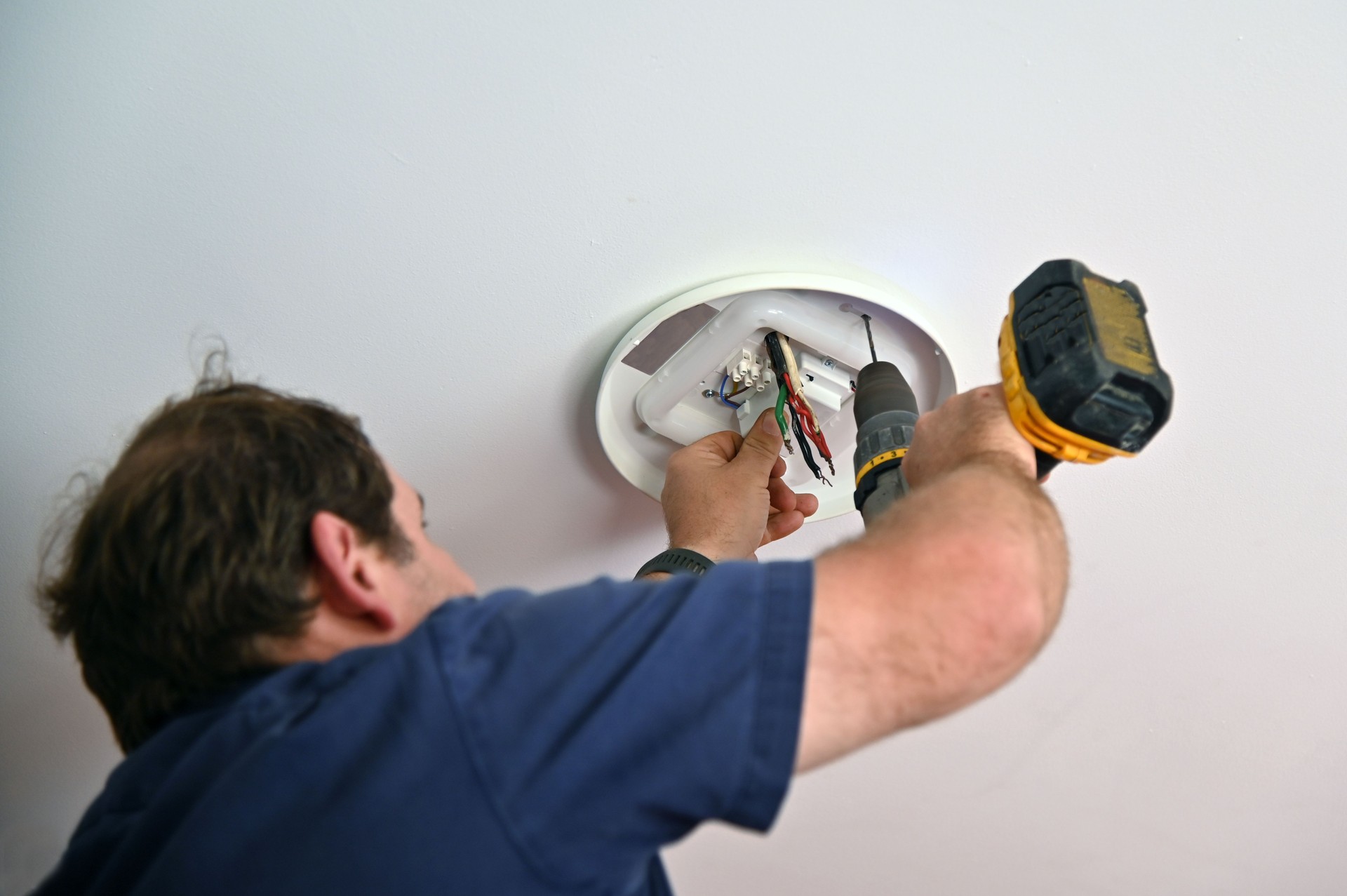 Electrician drilling a hole for a new  ceiling light fixture